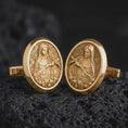 Load image into Gallery viewer, Gold plated Mary Magdalene cufflinks sit on textured volcanic rock in a dramatic studio macro shot, highlighting the sacred saint medallion design.
