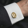Load image into Gallery viewer, A gold plated St Dominic cufflink is worn on a white cuff in a close-up lifestyle shot, styled as a thoughtful religious gift for Catholic men.

