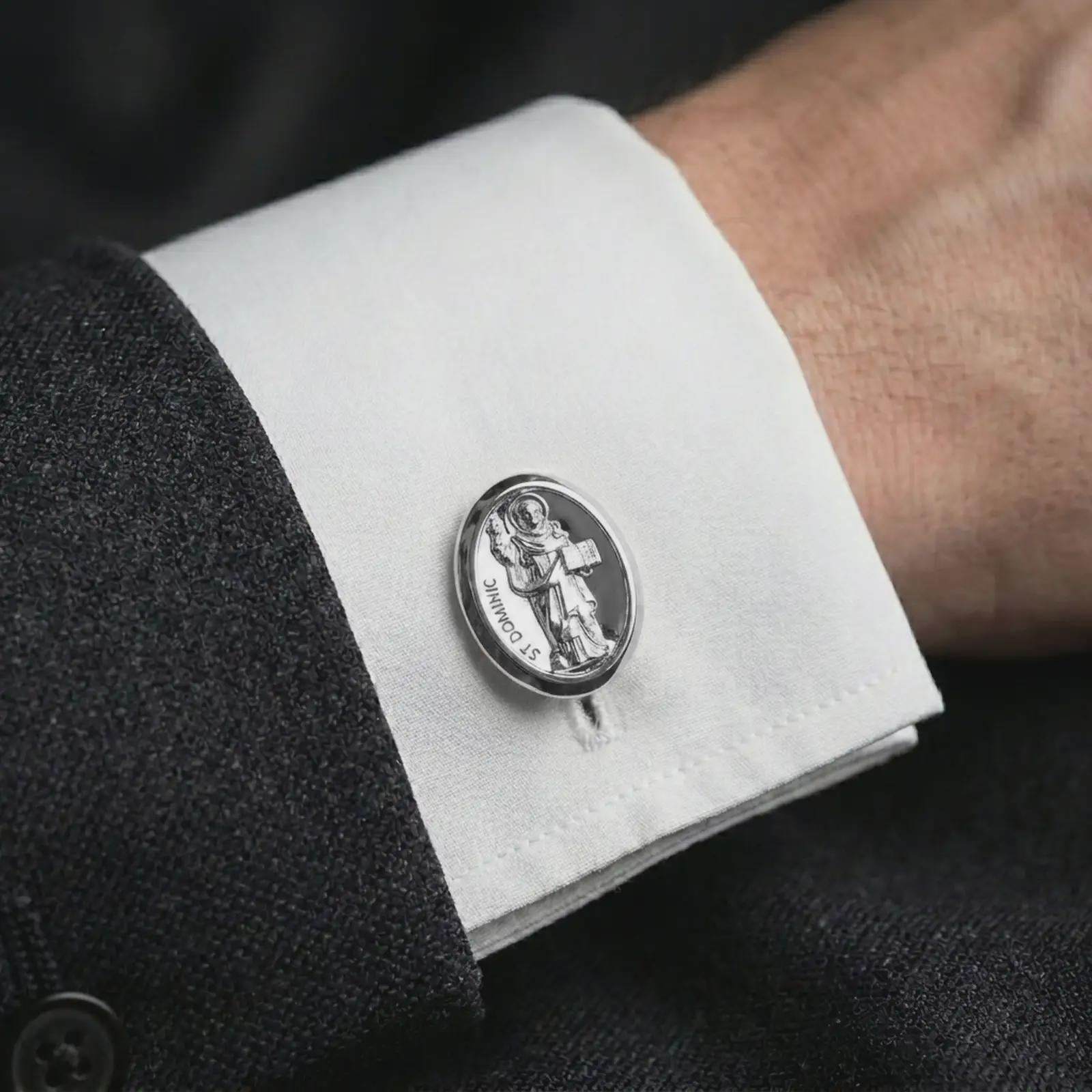A polished silver St Dominic cufflink is worn on a shirt cuff in a premium close-up lifestyle image, showing the saint relief clearly.