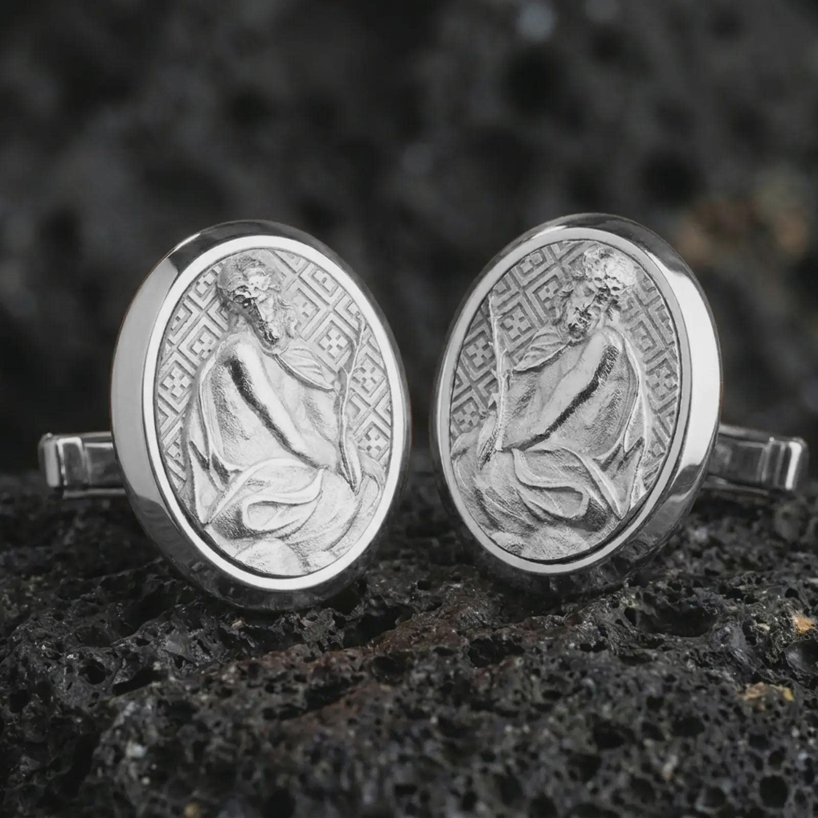 Polished silver Pensive Christ cufflinks are displayed on black volcanic rock in a premium macro studio close-up with detailed Christian devotional artwork.