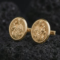 Load image into Gallery viewer, Gold plated Saint Joseph cufflinks photographed on black volcanic stone in a luxury studio close-up, emphasizing the patron saint carrying the Christ Child.
