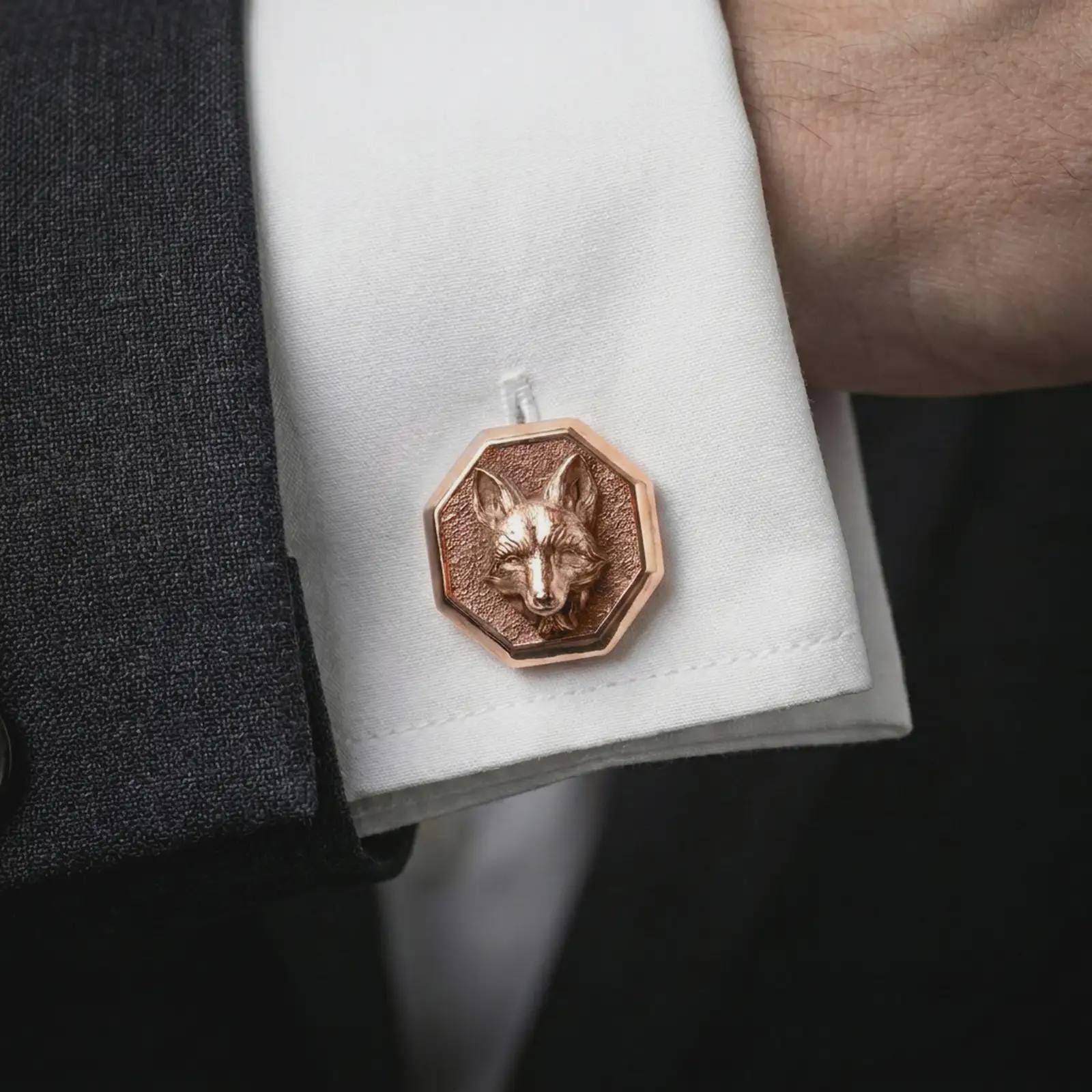 A rose gold plated fox head cufflink is worn on a shirt cuff in a close-up lifestyle composition, highlighting its octagon frame and sculpted fox design.
