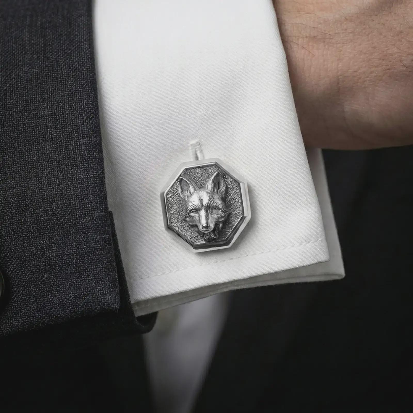 A polished silver fox head cufflink is worn on a shirt cuff in a premium close-up lifestyle image, showing the sculpted fox face clearly.