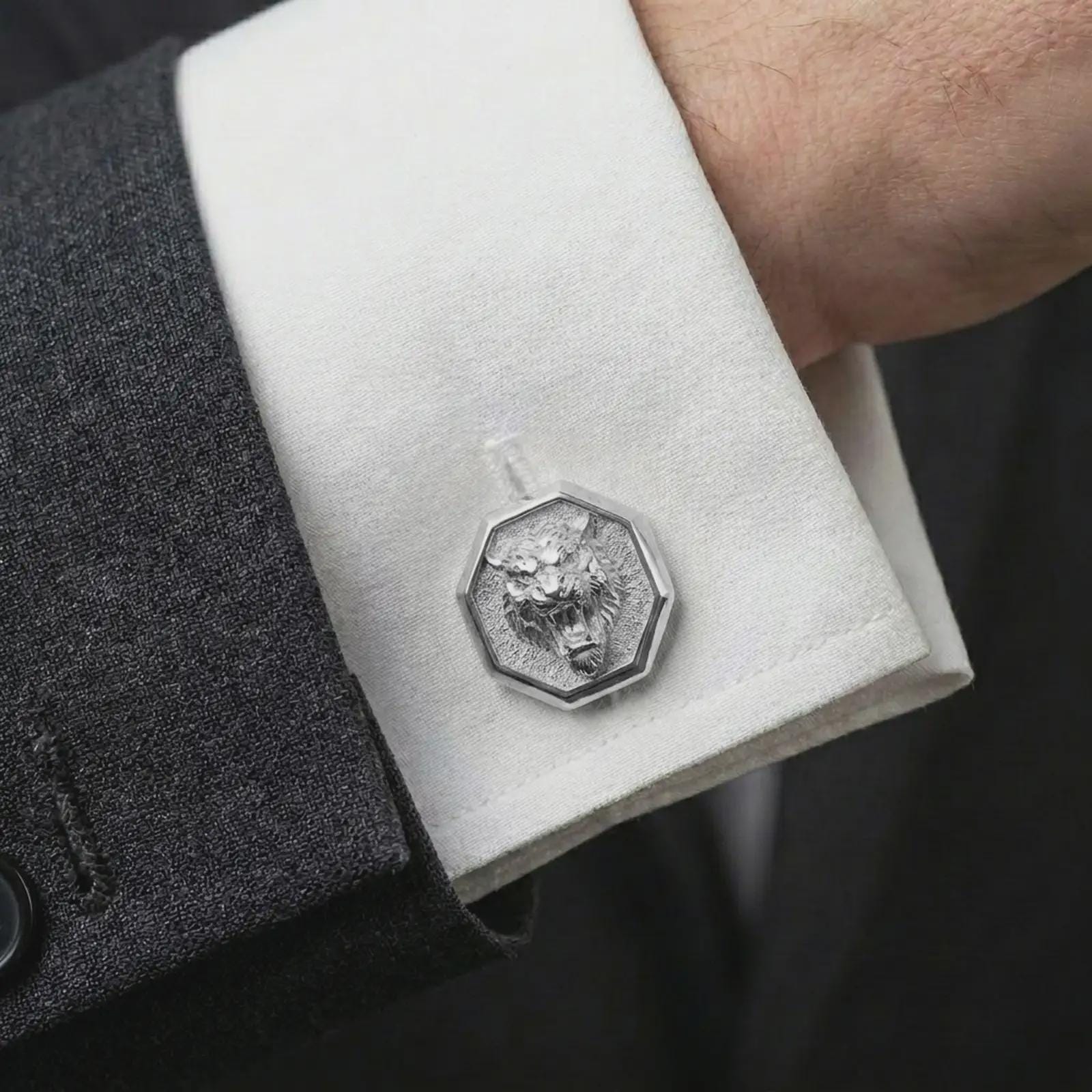 A polished silver tiger head cufflink is worn on a shirt cuff in a premium close-up lifestyle image, showing the sculpted roaring tiger face clearly.