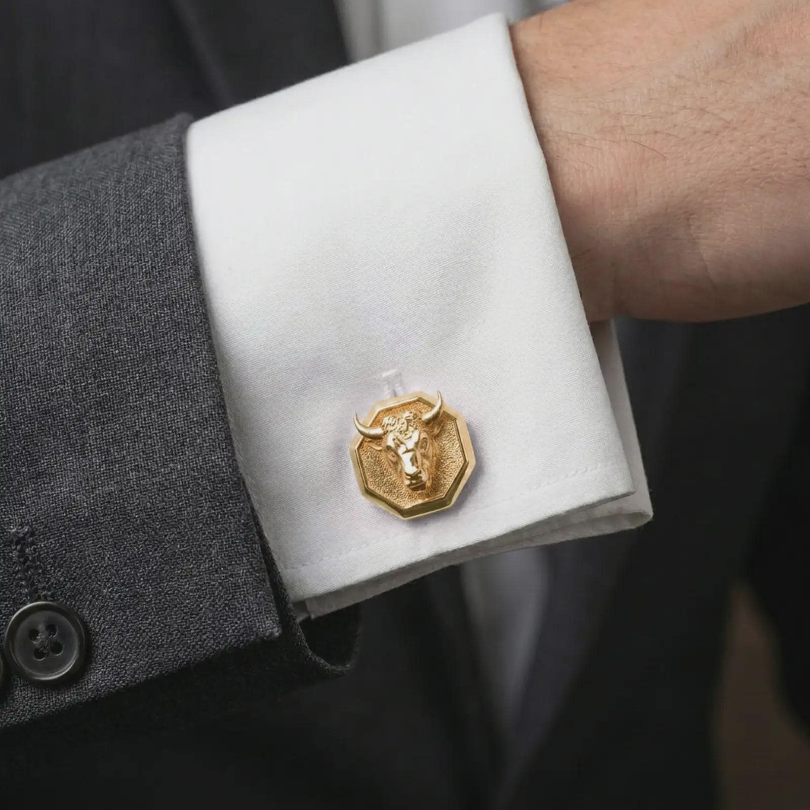 A gold plated bull head cufflink is worn on a white cuff in a close-up lifestyle shot, styled as a meaningful Taurus gift for men.