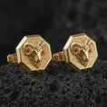 Load image into Gallery viewer, Gold plated ram head cufflinks sit on textured volcanic rock in a dramatic studio macro shot, highlighting the Aries-inspired animal motif and formal accessory design.
