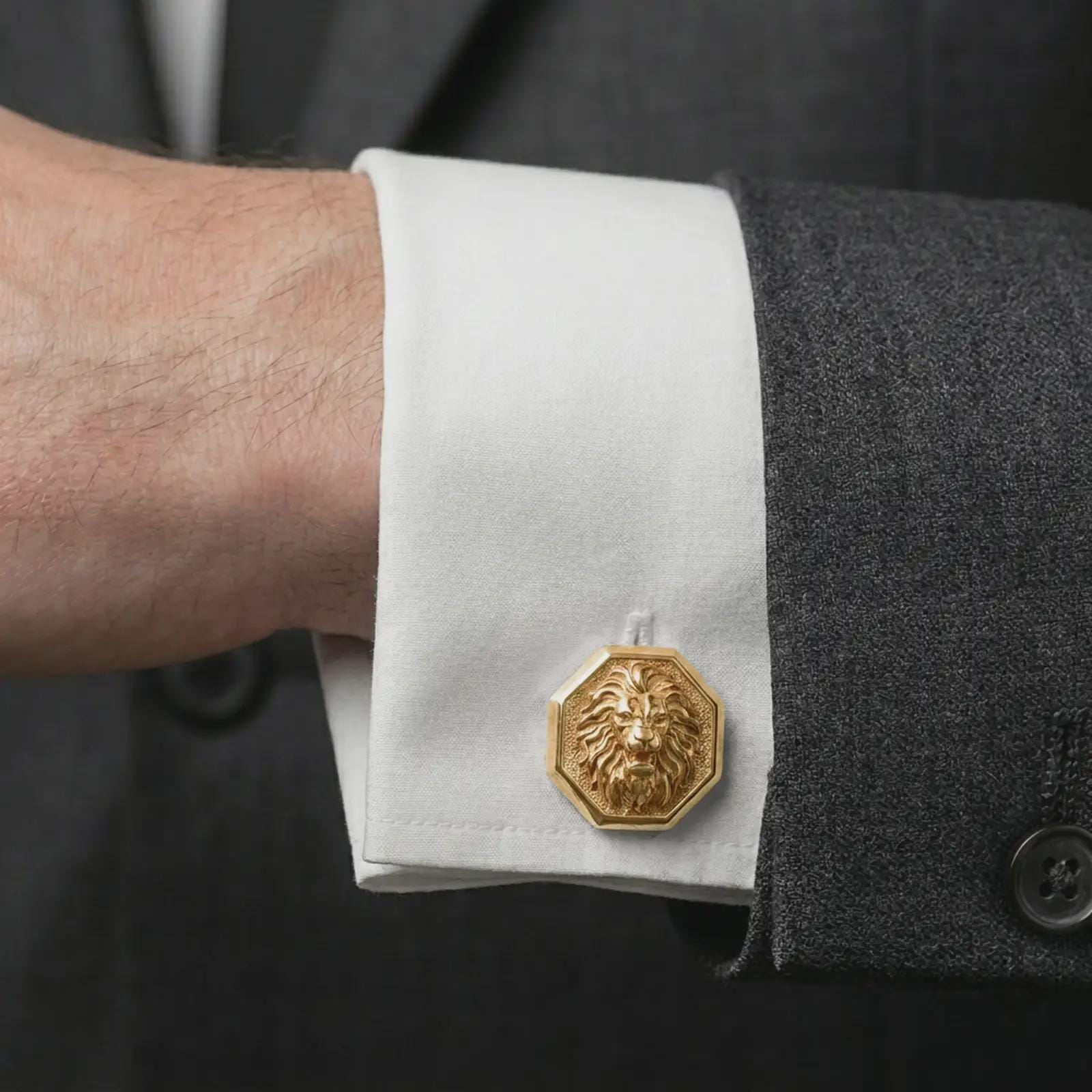 A gold plated lion head cufflink is worn on a white cuff in a close-up lifestyle shot, styled as a meaningful groomsmen accessory for men.