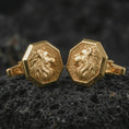 Load image into Gallery viewer, Gold plated lion profile cufflinks sit on textured volcanic rock in a dramatic studio macro shot, highlighting the noble animal motif and formal accessory design.
