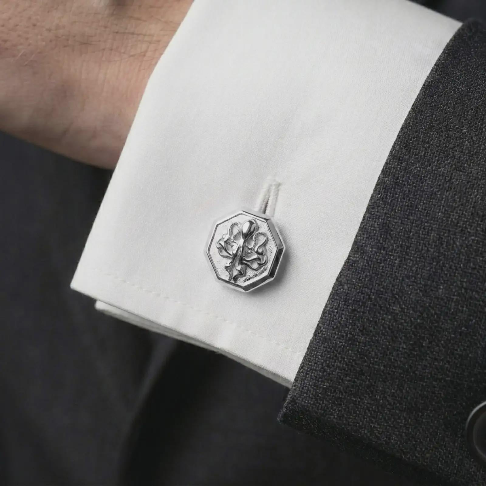 A polished silver octopus cufflink is worn on a shirt cuff in a premium close-up lifestyle image, showing the sculpted tentacles clearly.