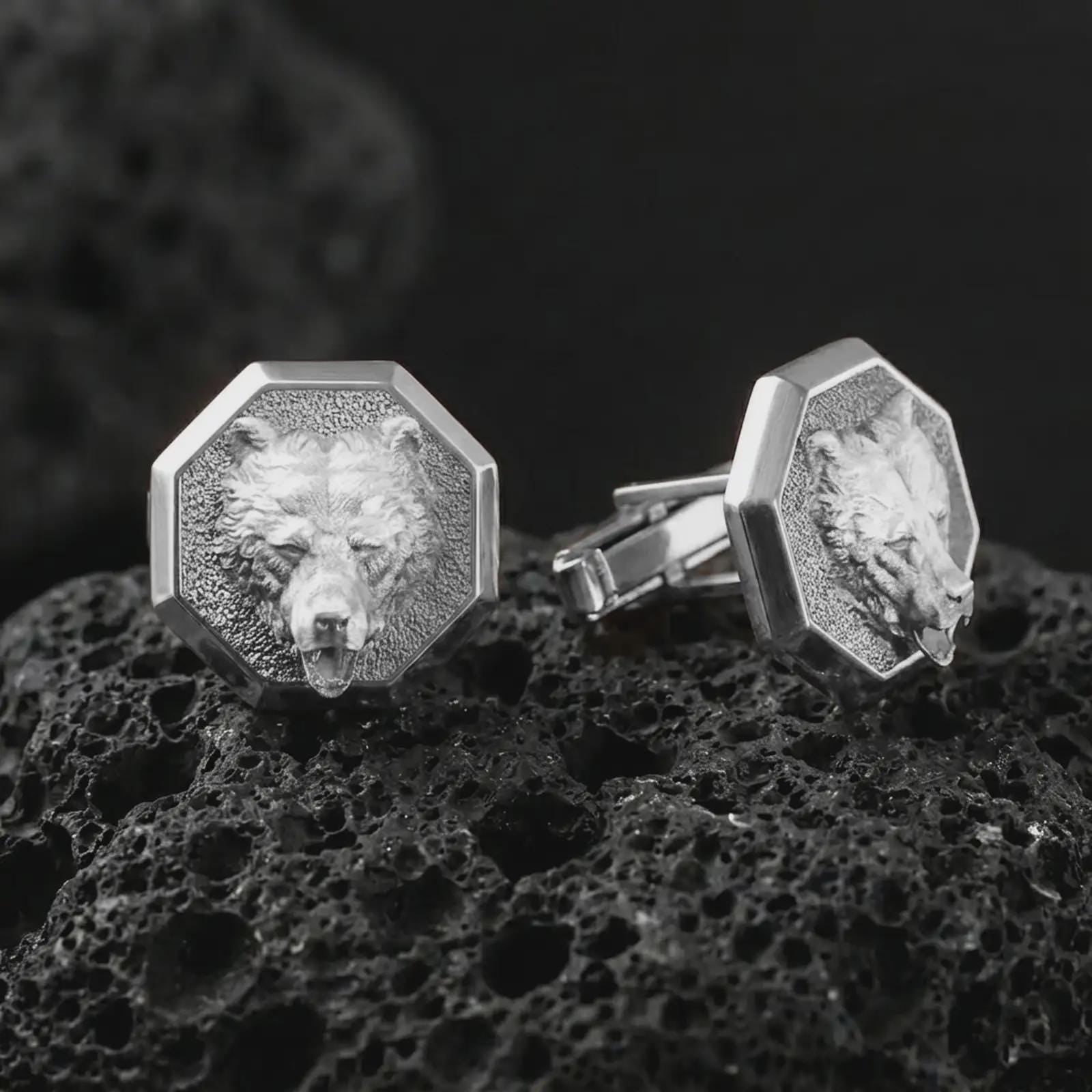 Polished silver bear head cufflinks are displayed on black volcanic rock in a premium macro studio close-up with detailed fur texture and clean geometric edges.