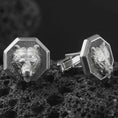 Load image into Gallery viewer, An oxidized bear head cufflink pair rests on dark volcanic rock in a macro studio close-up, showing a sculpted grizzly-inspired animal face inside octagon frames.
