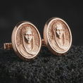 Load image into Gallery viewer, Rose gold plated Virgin Mary cufflinks are photographed on porous volcanic rock in a close-up studio composition with refined luxury lighting and religious detail.
