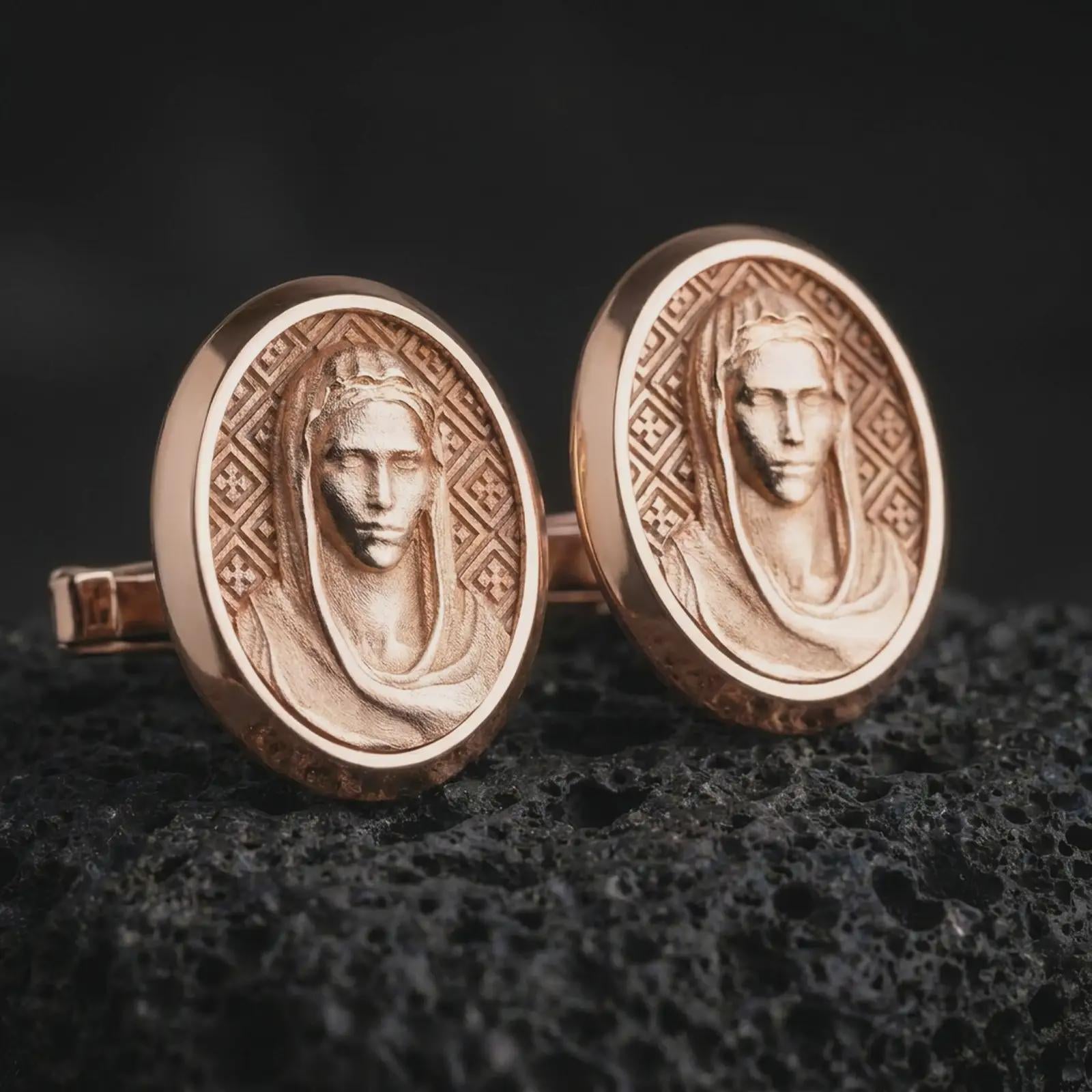 Rose gold plated Virgin Mary cufflinks are photographed on porous volcanic rock in a close-up studio composition with refined luxury lighting and religious detail.