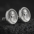 Load image into Gallery viewer, An oxidized Virgin Mary cufflink pair rests on dark volcanic rock in a macro studio close-up, showing a refined Marian portrait inside oval frames.
