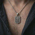 Load image into Gallery viewer, Oxidized German eagle shield pendant necklace worn on the chest, close-up lifestyle jewelry photo showing the heraldic eagle medallion on a spiga chain with dark clothing.
