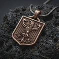 Load image into Gallery viewer, Bronze German eagle shield pendant necklace on textured volcanic rock, close-up studio shot highlighting the heraldic eagle relief, shield frame, feather details, and antique silver contrast.
