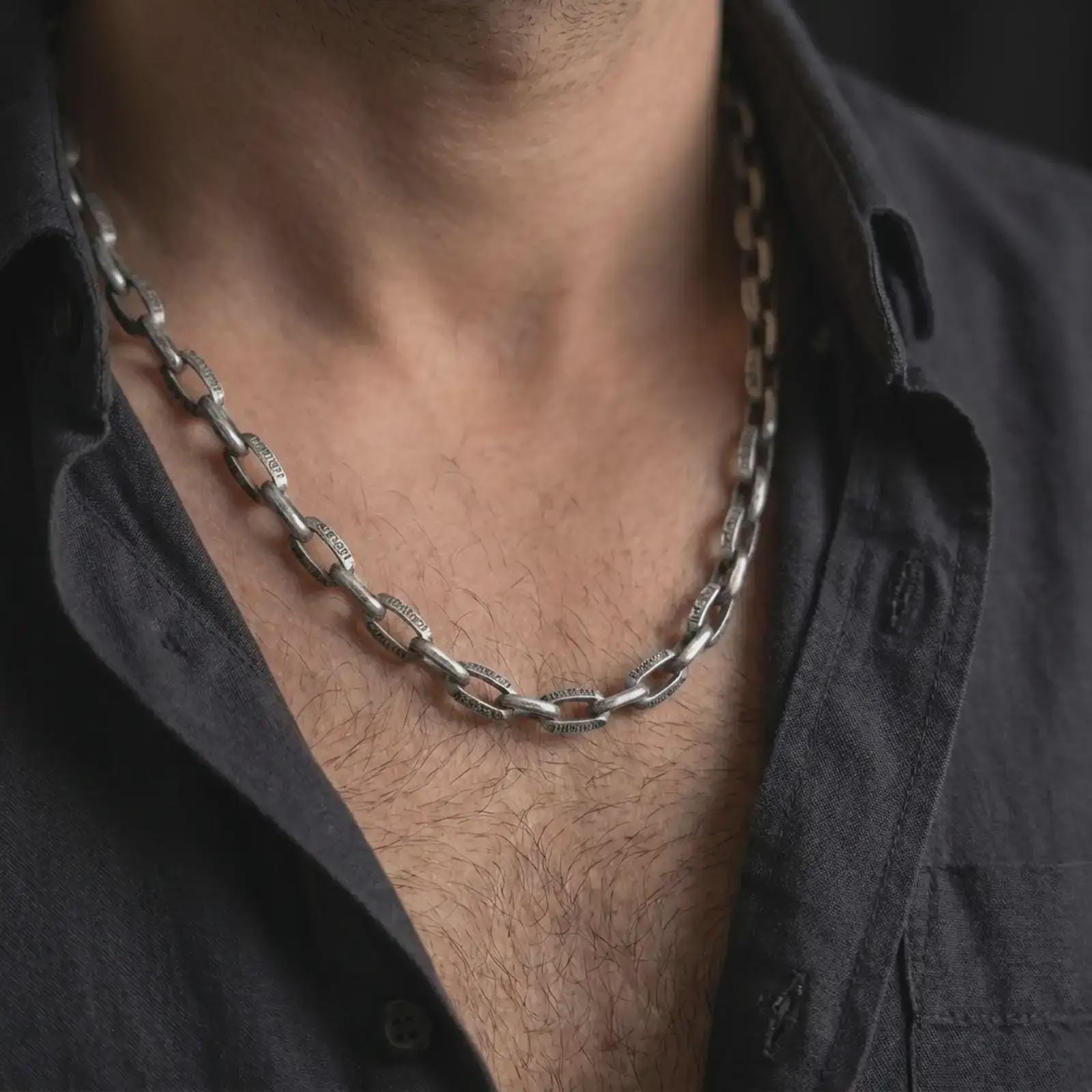 Oxidized Greek key chain necklace is worn on the neck in a close-up lifestyle shot, styled as a masculine everyday silver chain.