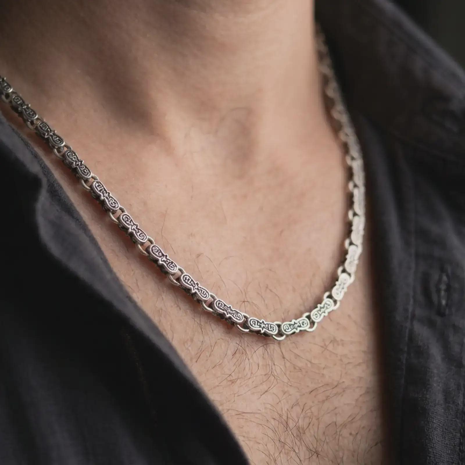 Oxidized Greek key chain necklace is worn on the neck in a close-up lifestyle shot, styled as a masculine everyday silver chain.