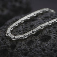 Load image into Gallery viewer, Polished silver Greek key chain necklace is displayed on black volcanic rock in a premium macro studio close-up with bright geometric link details.
