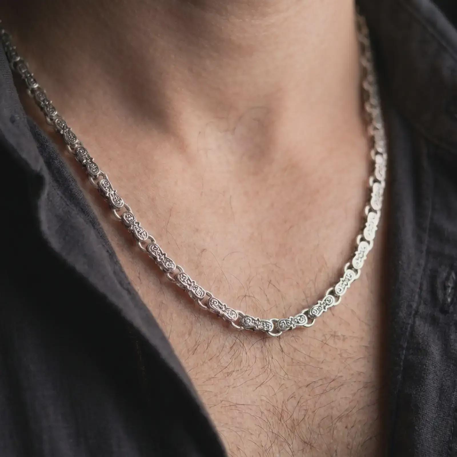Polished silver Greek key chain necklace is worn on the neck in a premium close-up lifestyle image, showing the clean Byzantine-inspired link structure.