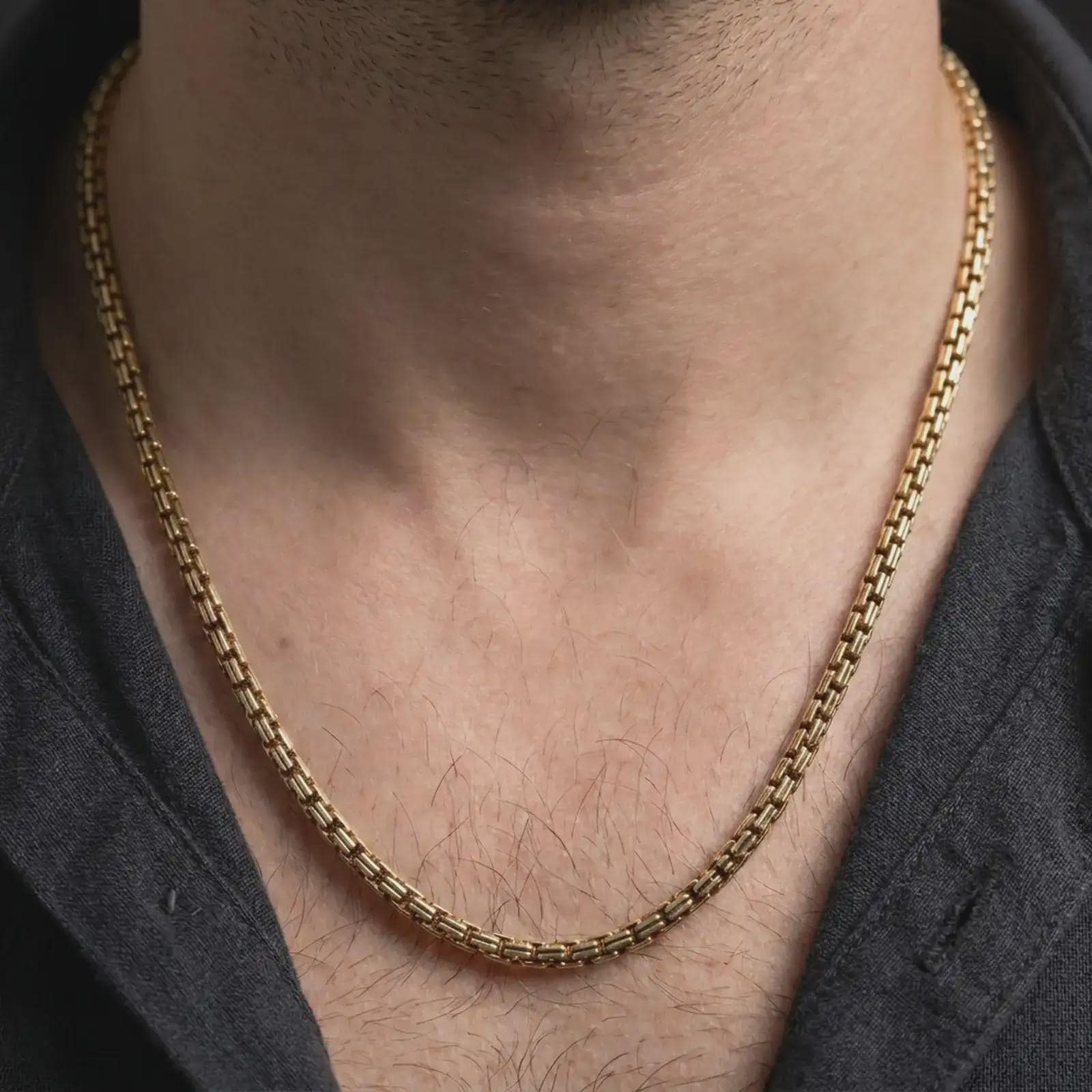 Gold plated box chain necklace worn in a lifestyle close-up, presenting a sleek architectural chain for modern styling.