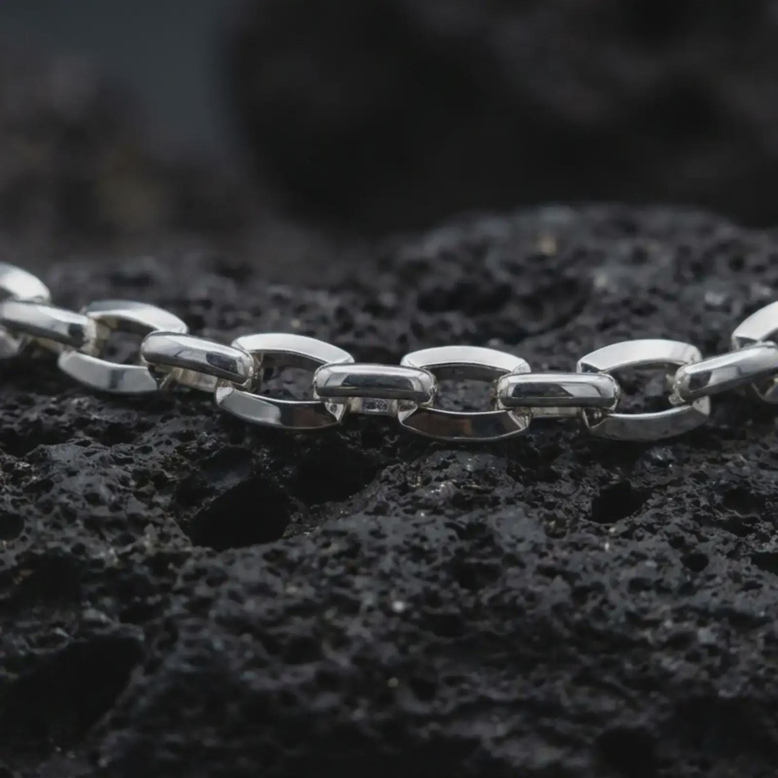 Polished silver mariner chain necklace on volcanic stone, highlighting the rounded links and nautical-inspired design.