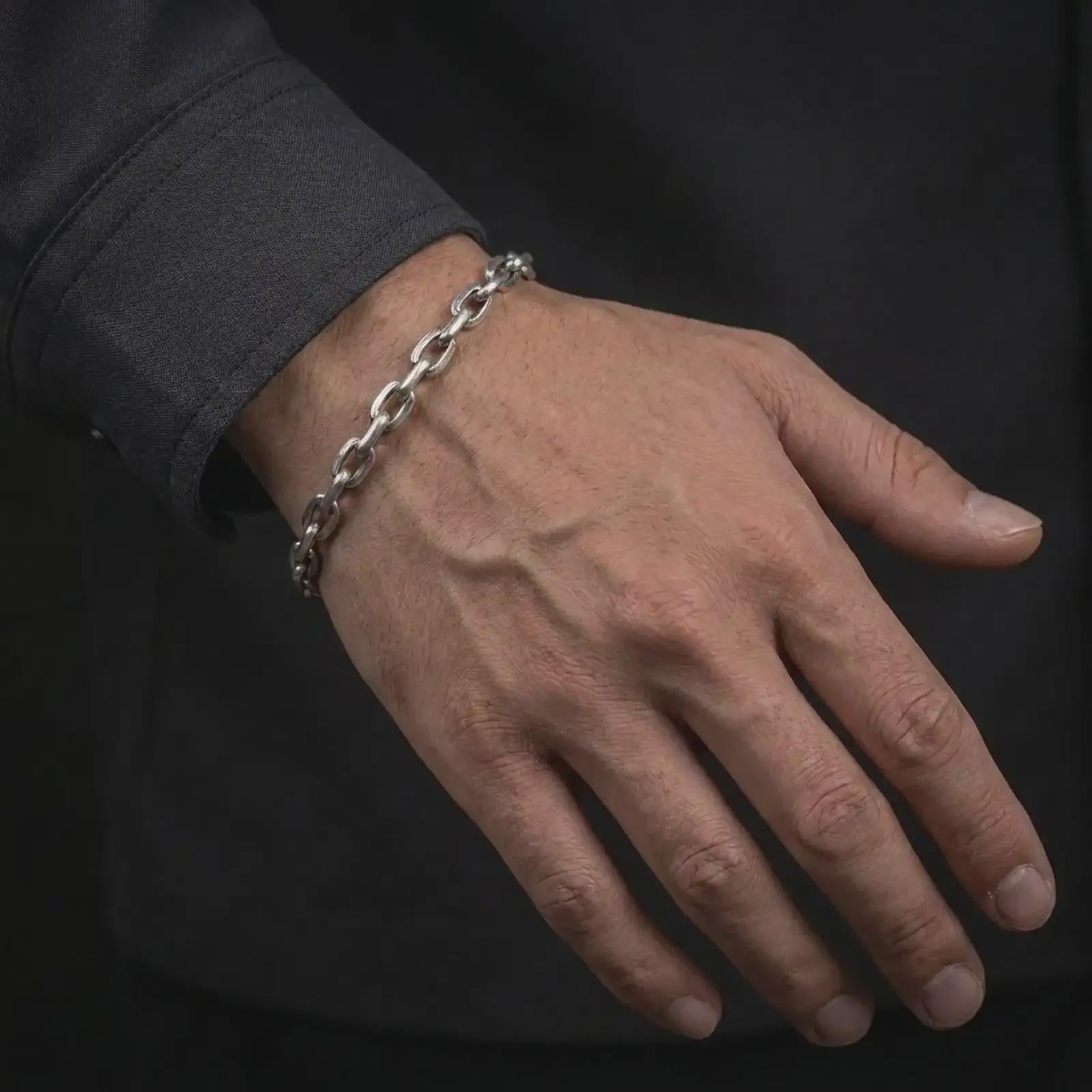 Oxidized silver anchor link bracelet worn on a male wrist, styled as a masculine everyday chain bracelet.