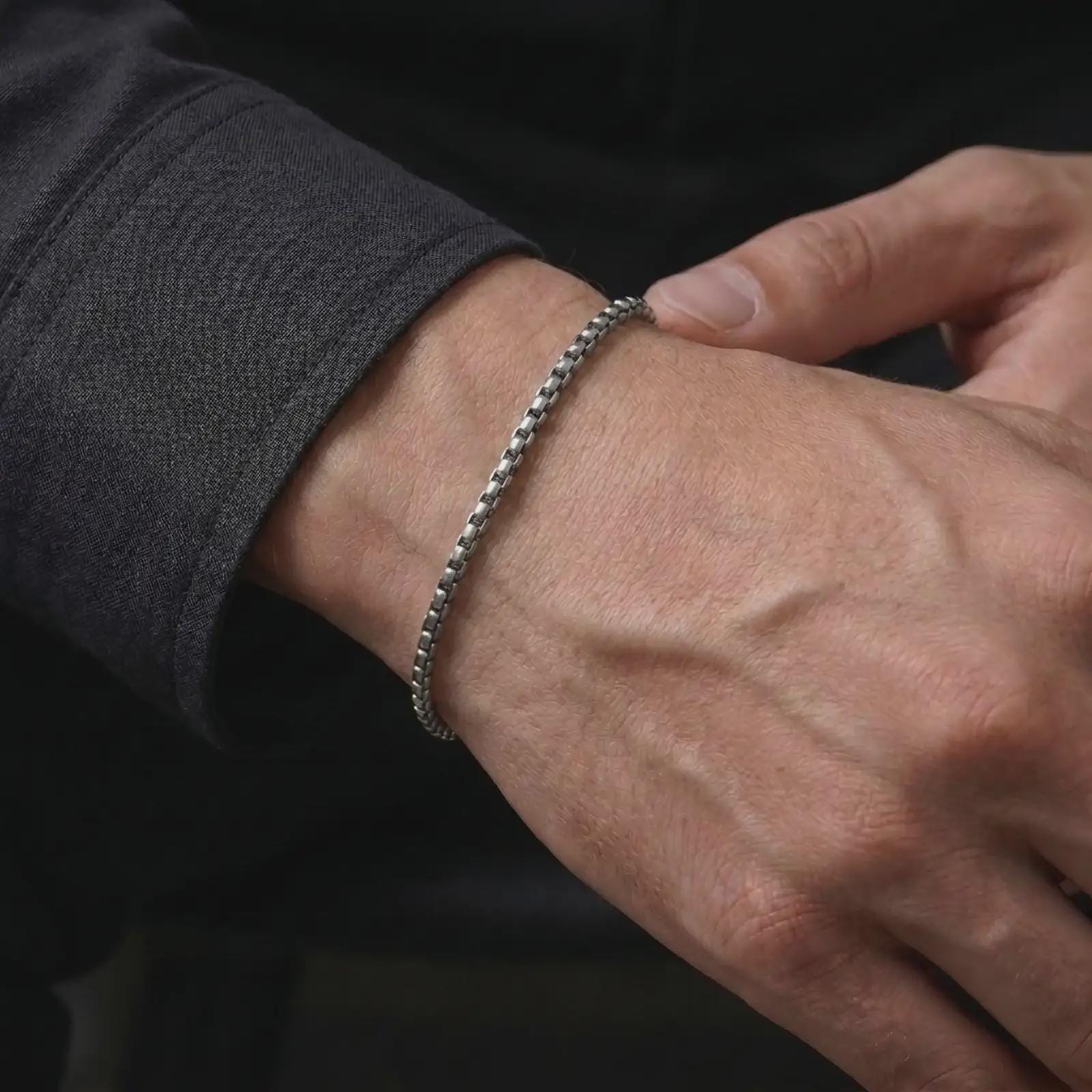 Oxidized silver box chain bracelet worn on a male wrist, showing its narrow fit and subtle vintage texture for everyday styling.