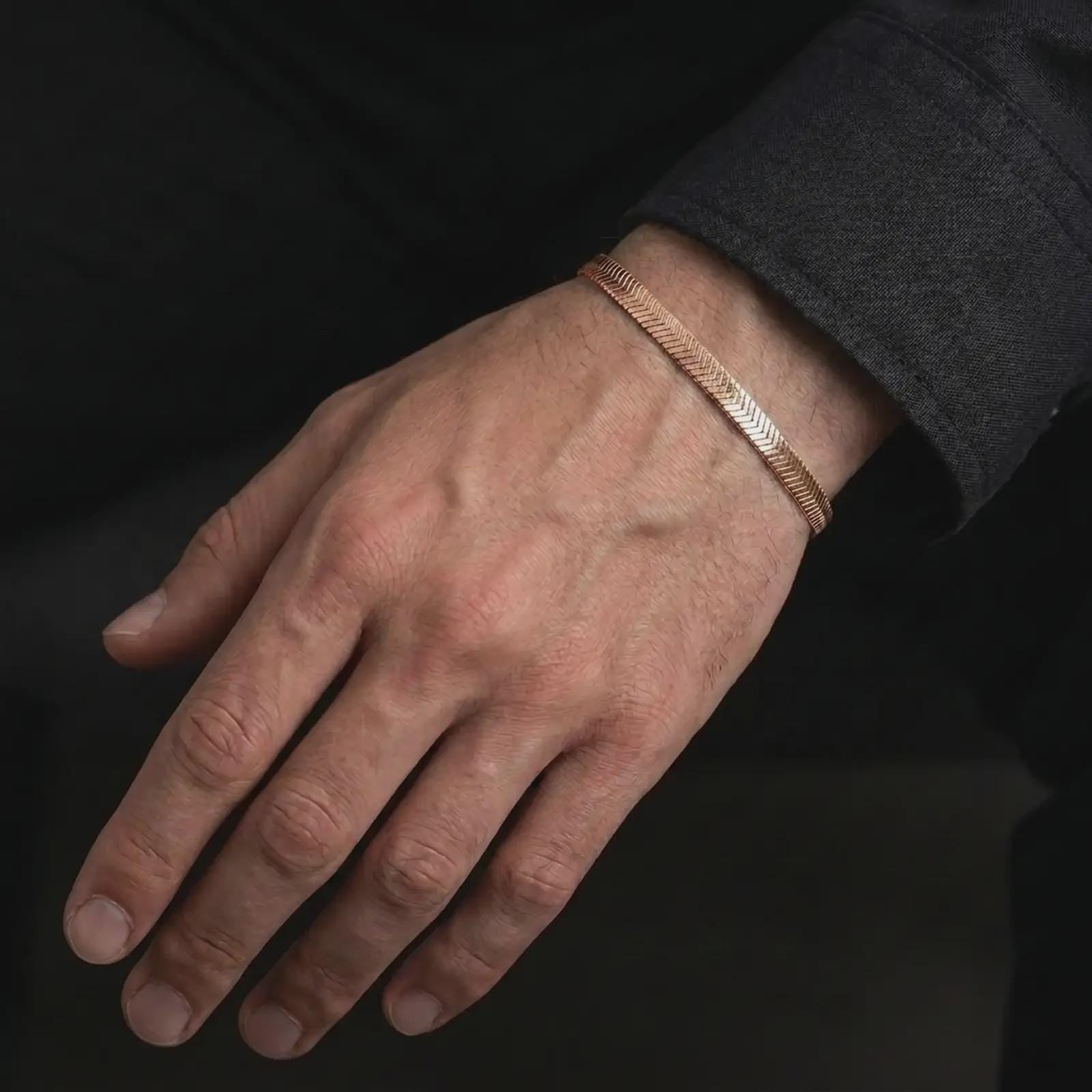 Rose gold plated herringbone chain bracelet worn on the wrist, designed as a slim modern bracelet with a warm metallic tone.