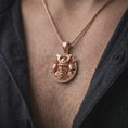 Load image into Gallery viewer, The rose gold plated samurai warrior pendant is worn on a man’s chest, showcasing the kabuto helmet, protective face mask, weapon details, and ornamental round frame in an elegant lifestyle shot.
