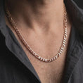 Load image into Gallery viewer, The rose gold plated 7mm Figaro necklace is worn naturally on a man’s chest, showcasing its flexible articulated links and traditional Italian-inspired chain design in an elegant lifestyle shot.
