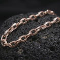 Load image into Gallery viewer, Rose gold plated Greek key chain necklace is photographed on porous volcanic rock in a close-up studio composition with refined luxury lighting and detailed links.
