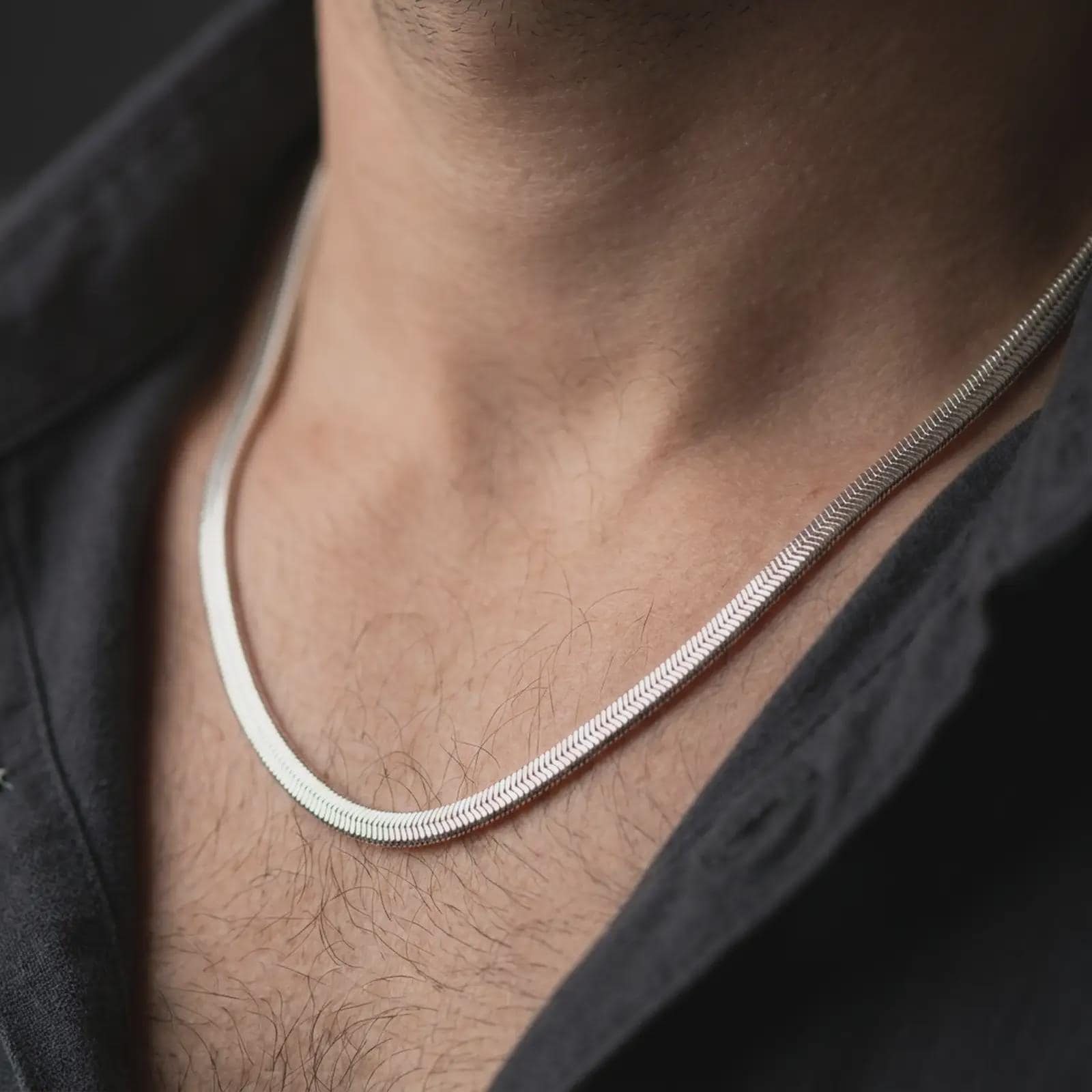 Polished silver snake chain worn in a close-up lifestyle shot, showing its smooth round profile and minimal silver finish.