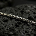 Load image into Gallery viewer, Oxidized sterling silver Venetian box chain displayed on black volcanic rock, showing its squared link structure and darkened detail.
