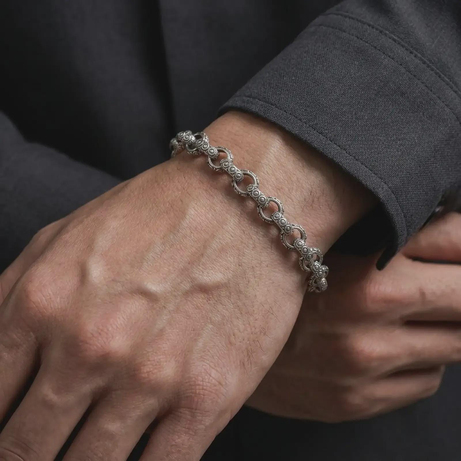 Oxidized sterling silver ornamental bracelet worn on a male wrist, showing its textured circle-link design and refined vintage character.
