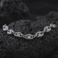 Load image into Gallery viewer, An 11mm mariner chain necklace with an oxidized finish rests on dark volcanic rock, showing substantial oval anchor links with recessed central bars in a macro studio close-up.
