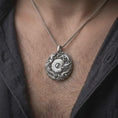 Load image into Gallery viewer, The polished silver Yin Yang dragon and phoenix necklace is worn on a man’s chest, with the detailed scales, flowing feathers, cloud patterns, and round symbolic medallion clearly visible in a premium lifestyle photograph.
