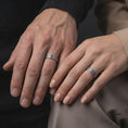 Load image into Gallery viewer, An oxidized geometric lattice ring is worn on a man’s and woman’s fingers, displaying the dark recessed crosshatch lines as a coordinated matching couple design in a close-up lifestyle shot.
