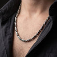 Load image into Gallery viewer, An oxidized Greek key necklace is worn on a man’s neck, displaying the dark recessed meander pattern and elongated sterling silver links in a masculine close-up lifestyle shot.
