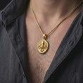 Load image into Gallery viewer, A gold plated octopus pendant is worn on a man’s neck with dark clothing, highlighting the bold kraken-inspired relief and nautical statement style in a refined close-up lifestyle shot.
