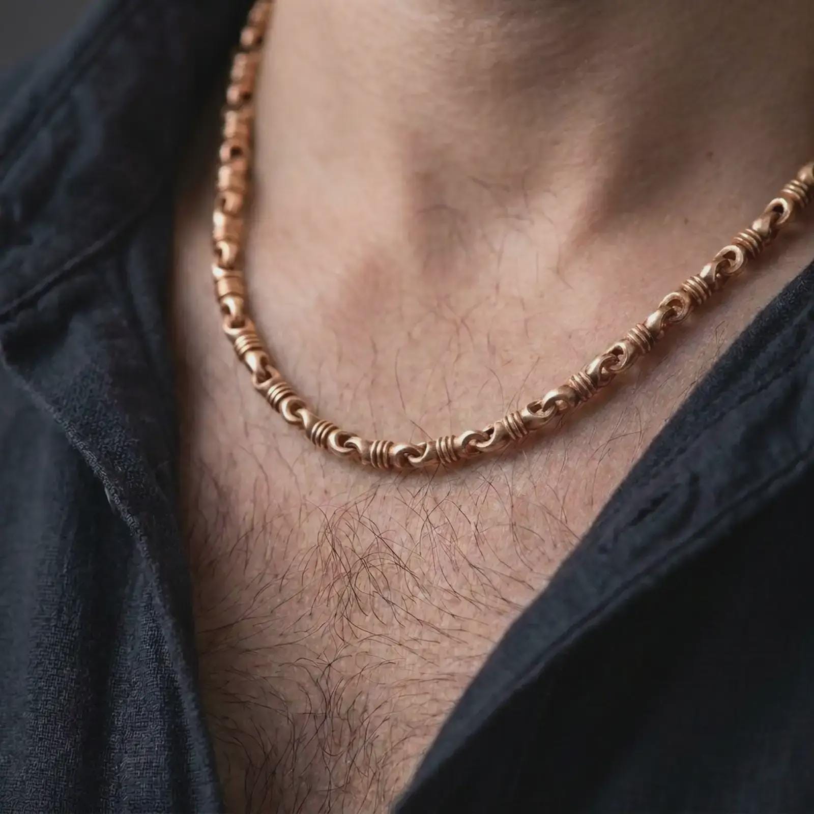 The rose gold plated ridged barrel necklace is worn naturally on a man’s chest, showcasing the cylinder link structure, polished surfaces, and refined masculine jewelry design.