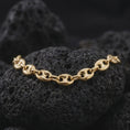 Load image into Gallery viewer, A gold plated 11mm anchor link necklace is displayed on rugged volcanic rock, featuring bold oval mariner links divided by distinctive central bars in a luxury macro studio close-up.
