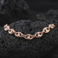 Load image into Gallery viewer, The rose gold plated 11mm mariner chain necklace rests on black volcanic rock, emphasizing its wide interlocking links and strong nautical profile in a refined macro studio image.
