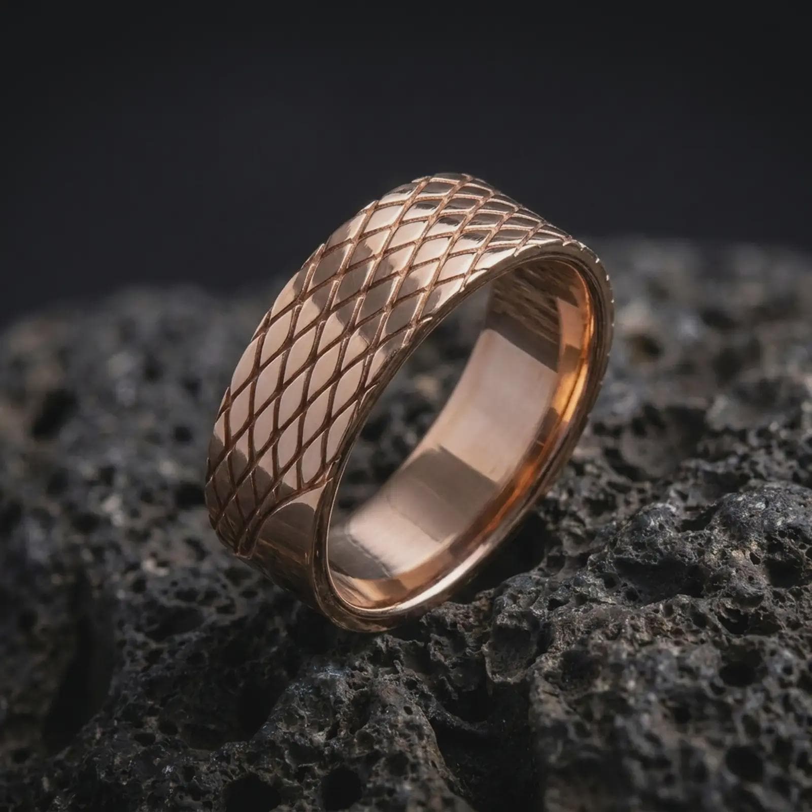 The rose gold plated lattice band is arranged on dark volcanic rock, emphasizing the symmetrical diamond texture, clean edges, and substantial geometric profile in a refined macro image.
