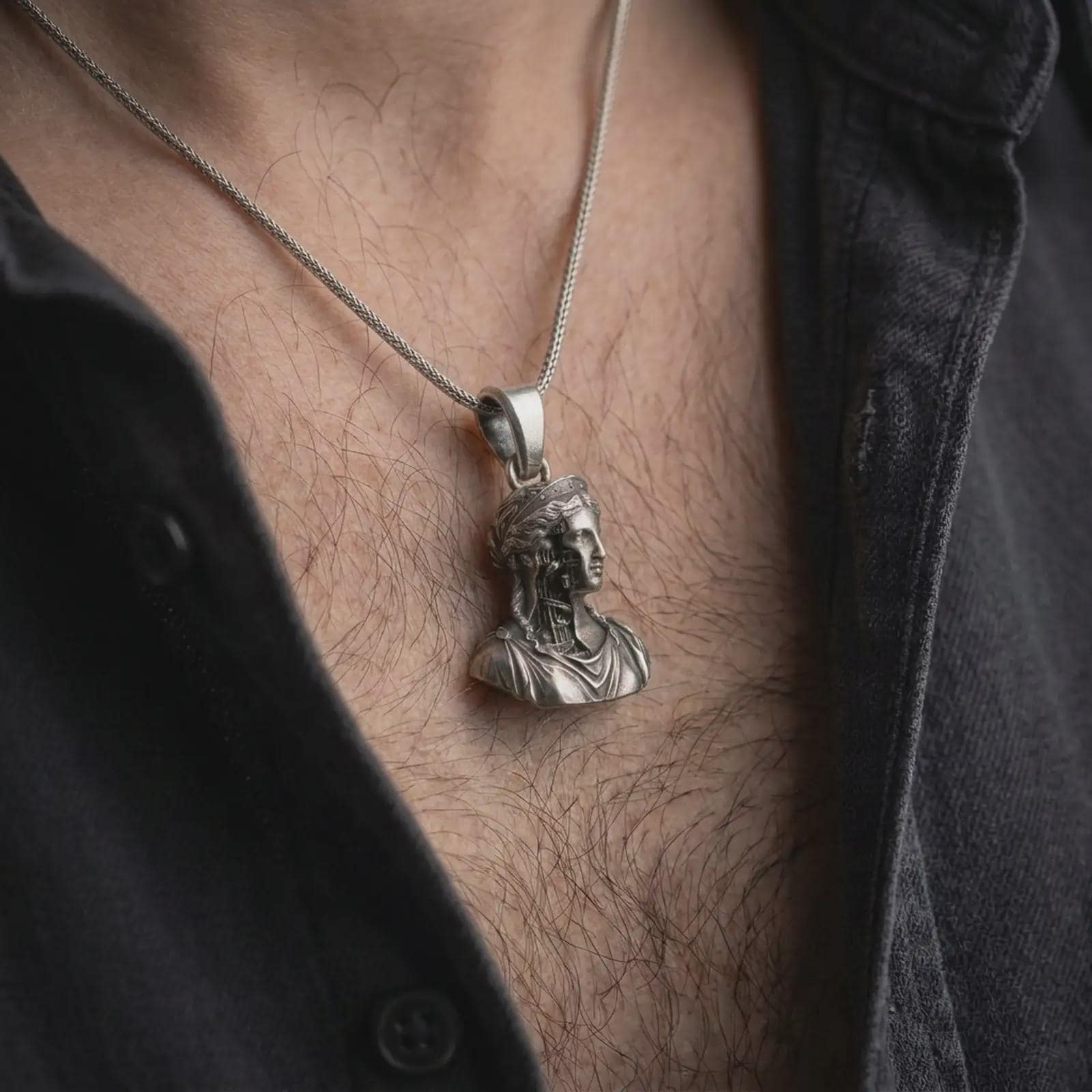Oxidized architectural bust pendant worn on neck in close-up lifestyle shot