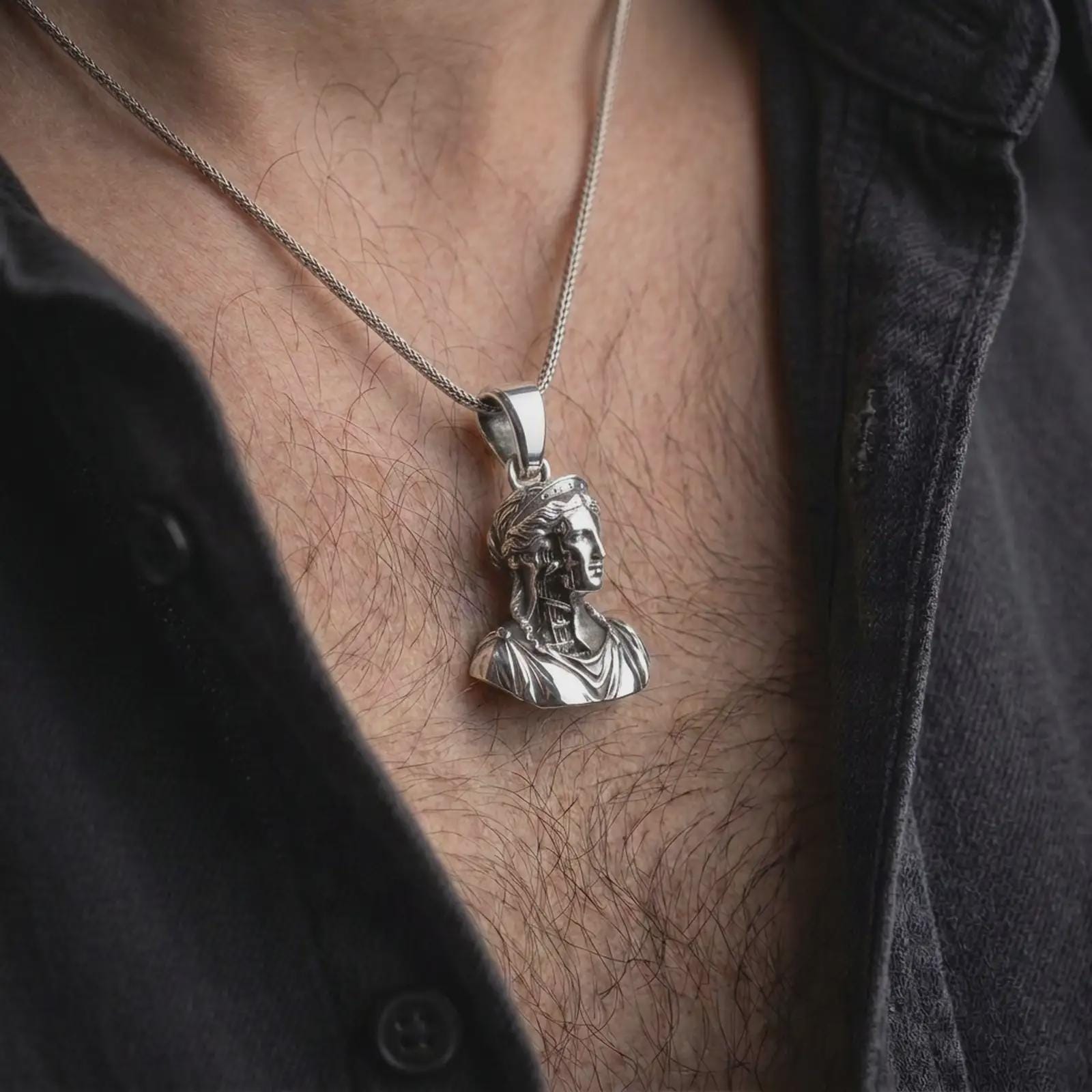 Polished silver architectural bust pendant worn on neck in close-up lifestyle shot