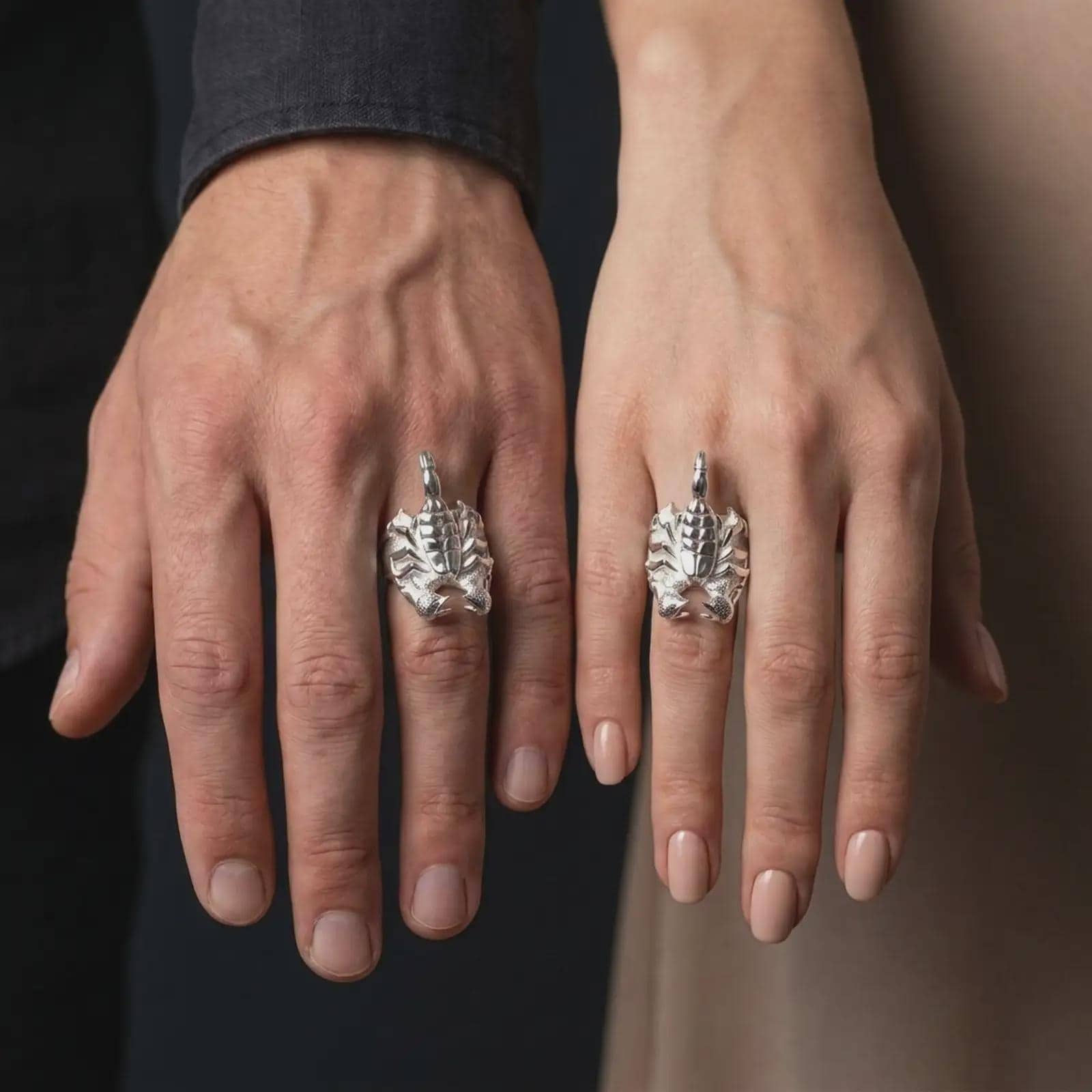 The polished silver scorpion ring is worn on a man’s finger, showing the sculpted arachnid body, segmented tail, textured claws, and substantial gothic band in a premium lifestyle photograph.