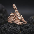 Load image into Gallery viewer, The rose gold plated scorpion ring is arranged on black volcanic rock, emphasizing the wide band, raised scorpion tail, claw details, and gothic animal-inspired construction in a refined macro studio image.
