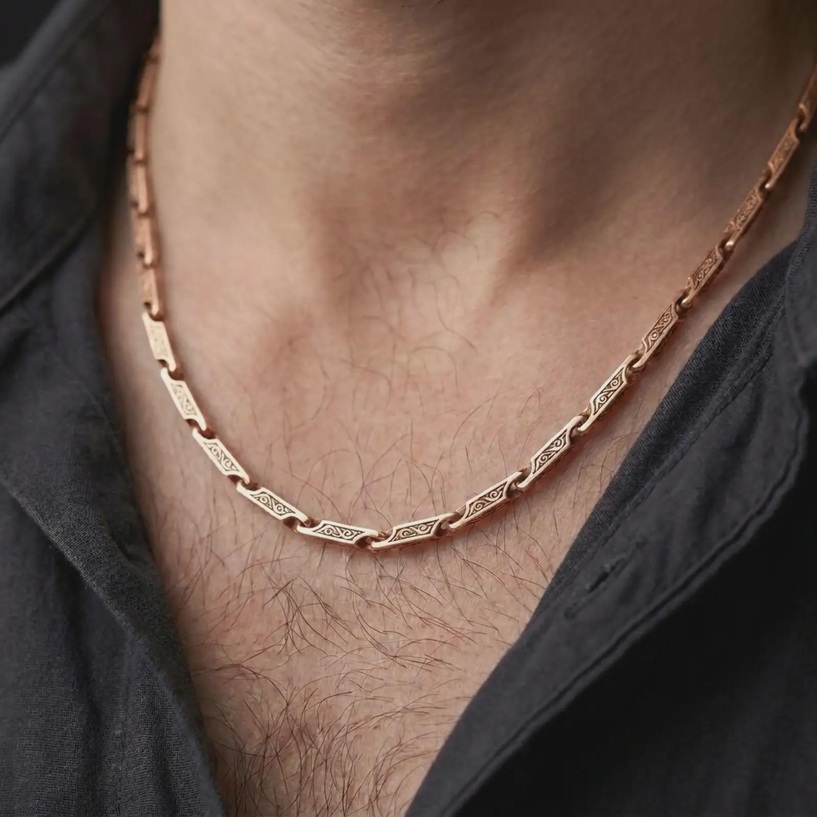 The rose gold plated ornate chain necklace is worn naturally on a man’s chest, showcasing the flowing scroll engravings, flexible link construction, and masculine jewelry design.