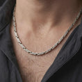 Load image into Gallery viewer, An oxidized scroll chain necklace is worn on a man’s neck, displaying dark recessed engravings, rectangular sterling silver links, and a bold masculine silhouette in a close-up lifestyle shot.
